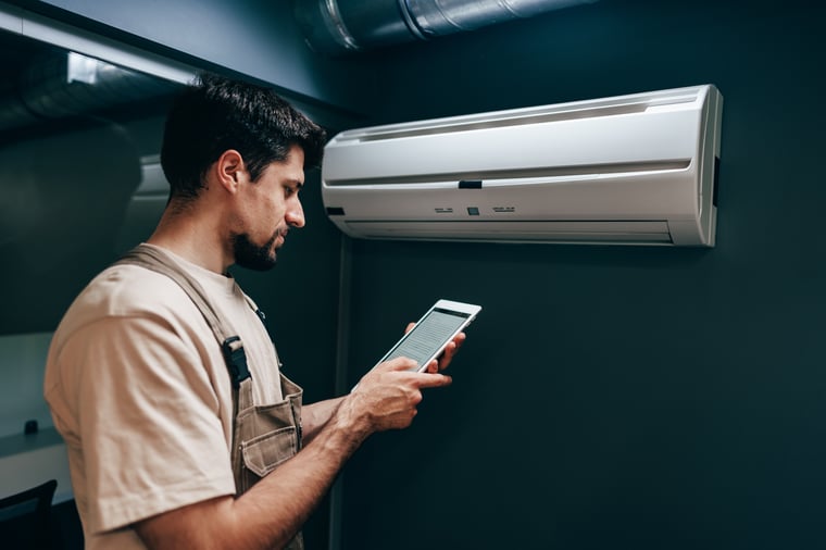 Hvac technician checks air conditioning unit using tablet