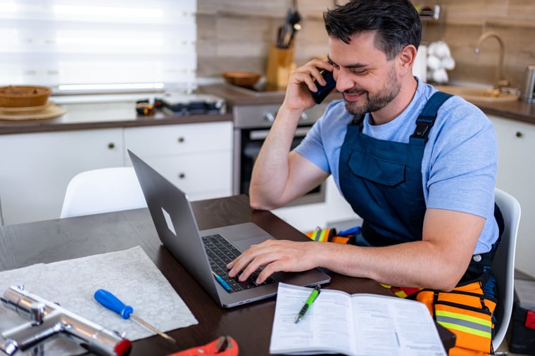 Contractor working on a laptop while talking on phone 